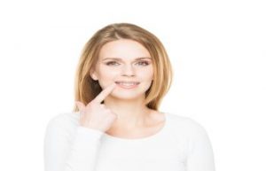 Woman Pointing at Her Smile While Wearing Invisalign BracesJohns Creek GA