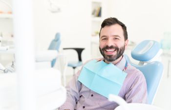 A satisfied smiling middle-aged man in a dental chair during an appointment., 