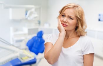 A concerned woman with a dental pain in a dentist office., 