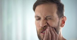 man suffering from pain caused by mouth sores