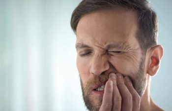 man suffering from pain caused by mouth sores