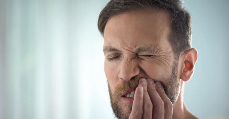 man suffering from pain caused by mouth sores, 