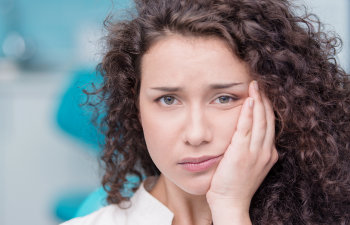 young woman holds her jaw with pain, 