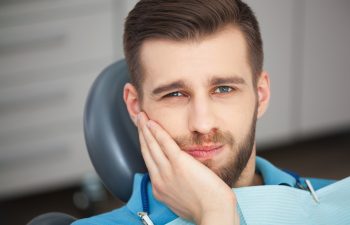 Shot of a young man with tooth pain while sitting in a dentist's chair.