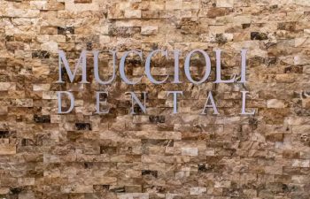 Muccioli Dental logo sign on stacked stone accent wall