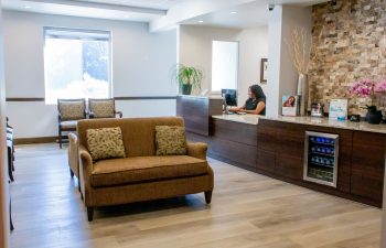 Reception desk with staff member and waiting area sofa