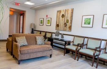 Dental office waiting room with brown sofa and patterned armchairs