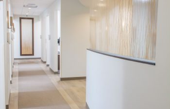Curved hallway with framed wall art and treatment room entrances