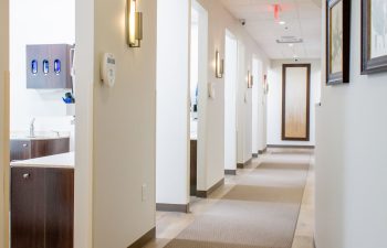 Hallway featuring wall-mounted hand sanitizer and supply dispensers